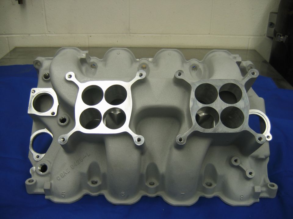 Aluminum dual-quad V8 intake manifold on a blue surface