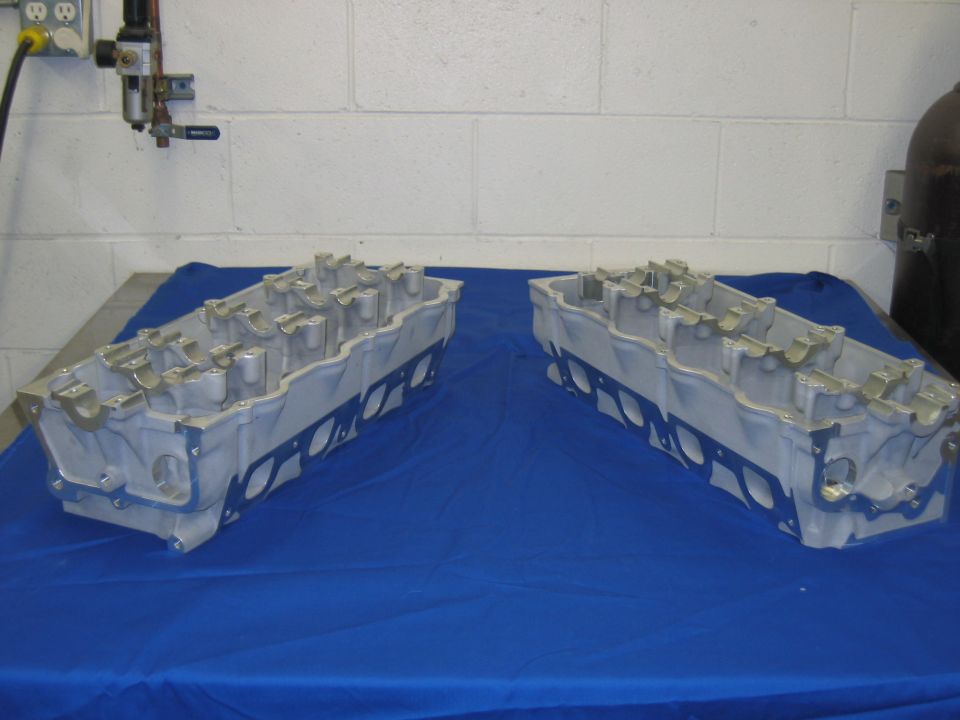 Pair of aluminum cylinder heads on blue cloth in a workshop