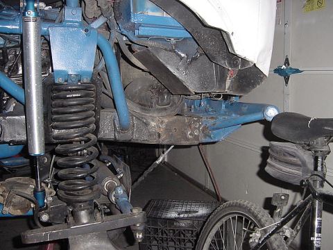 1971 Ford Bronco - The underside of a modified vehicle shows heavy-duty suspension components and a blue-painted frame.