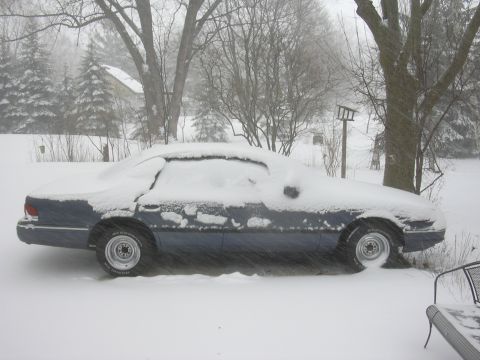 1996 Ford Crown Victoria - A blue 1996 Ford Crown Victoria sits covered in snow during a winter storm.