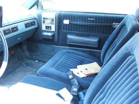 1991 Ford LTD Crown Victoria - The interior of a car shows blue velour seats and door panels with "Brougham" badging.