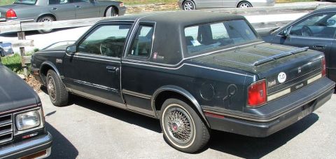 1991 Ford LTD Crown Victoria - This dark coupe features wire wheels and a "Custom Cruiser" badge, suggesting it is not a 1991 Ford Crown Victoria LTD.