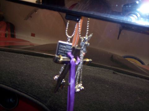 1972 Ford Ranchero - Hanging ornaments, including a cross and a religious plaque, are visible from the interior of a vehicle.