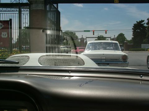 1972 Ford Ranchero - A white 1962 Ford Falcon sedan with blue trim is seen from inside another vehicle, with a pink car visible behind it.