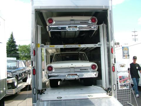 1972 Ford Ranchero - A man stands next to a trailer loaded with two classic Ford sedans, possibly being transported to a car show.