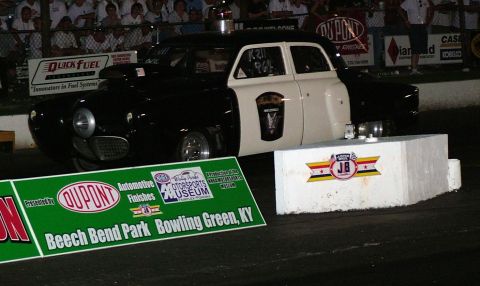 1972 Ford Ranchero - A modified drag car, painted black and white with a police department emblem, sits at the starting line.