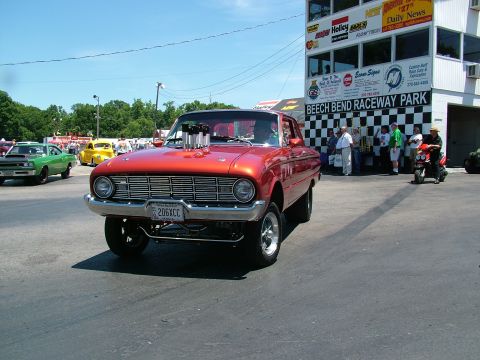 1972 Ford Ranchero - A modified classic car with a large engine sits on the track at a raceway, with spectators and a tower in the background.