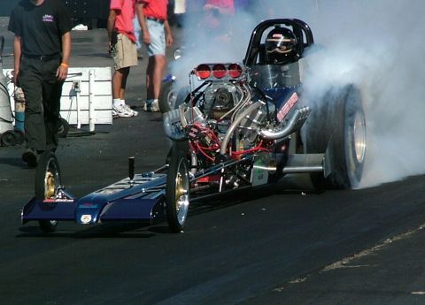 1972 Ford Ranchero - A dragster is seen on a track, with smoke billowing from its rear tires.
