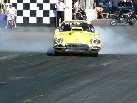 1972 Ford Ranchero - Yellow 1959 Corvette drag car performs a burnout at the starting line, generating smoke.