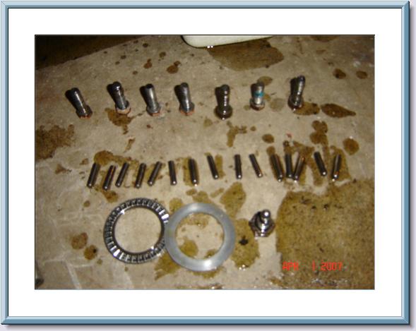 Transfer case teardown parts on concrete: pins, needle bearing, thrust washer and shafts