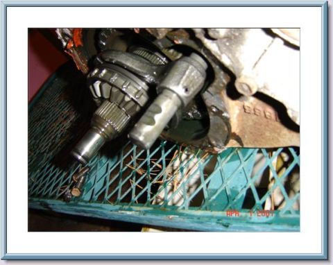 1978 Ford Bronco - A close-up view of internal gears and shafts from a vehicle's transfer case, resting on a green metal grate.