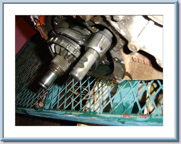 Disassembled transfer case internals with splined shafts on a green metal shop table