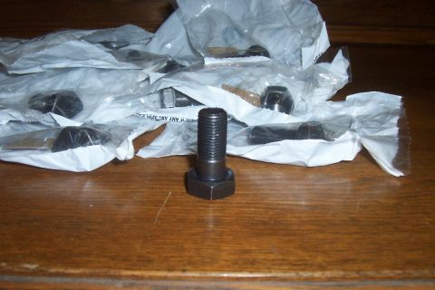 1994 Ford F-150 - Several bolts are shown in their packaging, with one prominent bolt in the foreground on a wooden table.