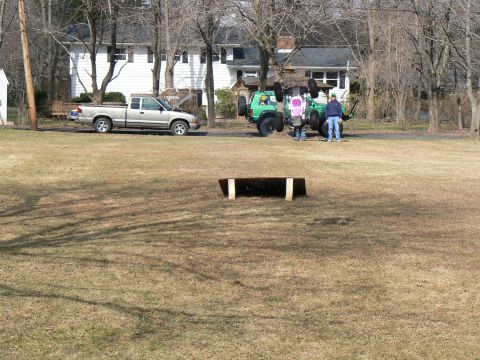 1994 Ford Bronco - A green Jeep is overturned in a grassy yard, with a silver pickup truck parked nearby.