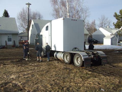 1990 Ford Bronco - A white semi-trailer truck is parked on muddy ground, with several people standing nearby.