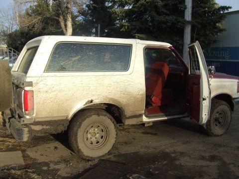 1990 Ford Bronco - This 1990 Ford Bronco, seen here in a muddy backyard setting, features a two-tone paint scheme and a red interior.