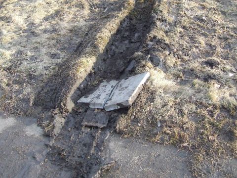 1990 Ford Bronco - Trench dug in muddy ground with dry grass, two concrete slabs placed across it.