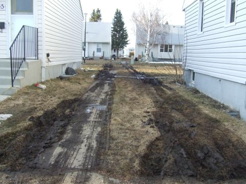 1990 Ford Bronco - A muddy driveway shows evidence of recent vehicle activity, with churned earth and tire marks.