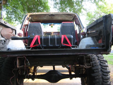 1979 Ford Bronco - The rear of a modified 1978 Ford Bronco, modified with large tires and an auxiliary fuel tank, is visible with the tailgate open.