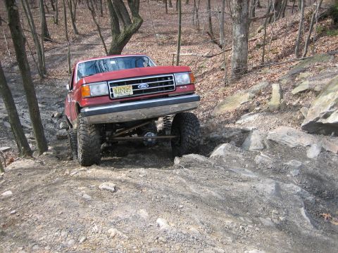 1990 Ford Bronco - This red 1990 Ford Bronco 4x4 is shown tackling a challenging rocky incline during an off-road excursion.