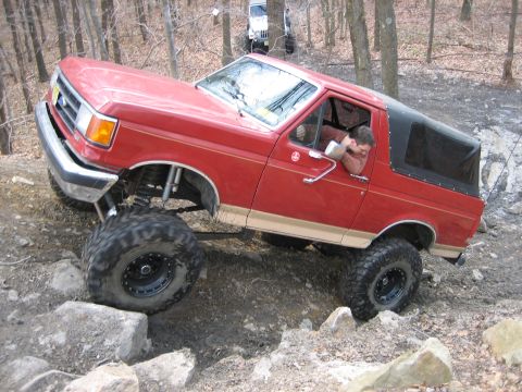 1990 Ford Bronco - This modified SUV is tackling a challenging off-road course with large tires and a lifted suspension.