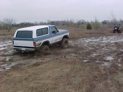 1978 Ford Bronco - This 1978 Ford Bronco navigates a muddy off-road course, with another vehicle visible in the background.