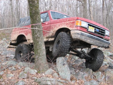 1990 Ford Bronco - This modified Ford Bronco navigates a challenging off-road course with large tires and a lifted suspension.