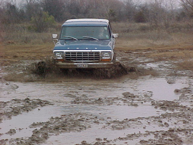 1978 Ford Bronco driving through a muddy field