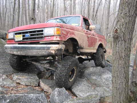 1990 Ford Bronco - This 1990 Ford Bronco is shown off-roading through a rocky, wooded area.