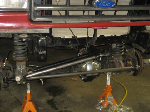 1990 Ford Bronco - Front suspension and steering components of a 1990 Ford Bronco, supported by jack stands.