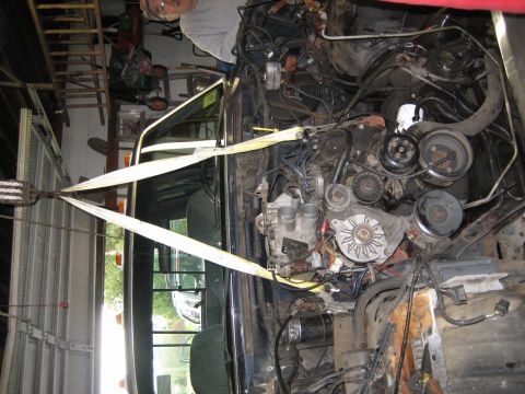 1990 Ford Bronco - Engine being removed from a vehicle in a garage setting.