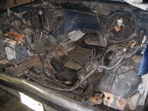 1990 Ford Bronco - The engine bay of a vehicle is shown with exposed components and wiring, indicating a disassembled state.
