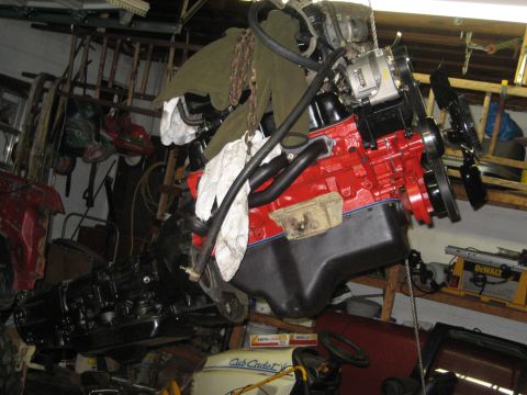 1990 Ford Bronco - A red engine block, likely a Ford 302 V8, is suspended by chains in a cluttered garage setting.