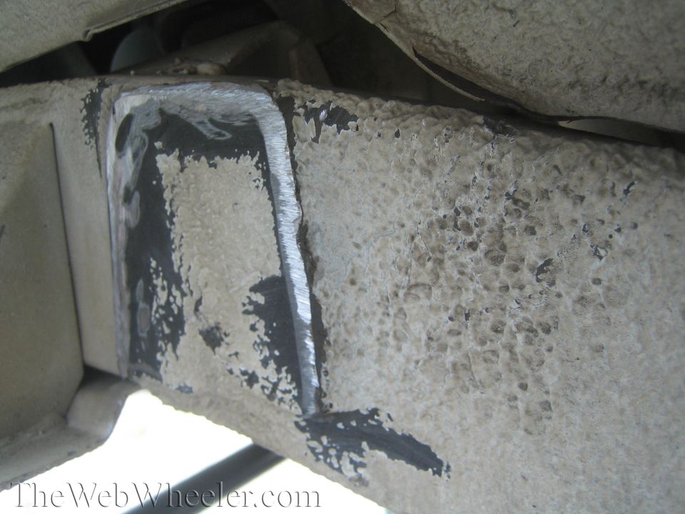 Close-up of a modified vehicle frame with cut marks and textured paint