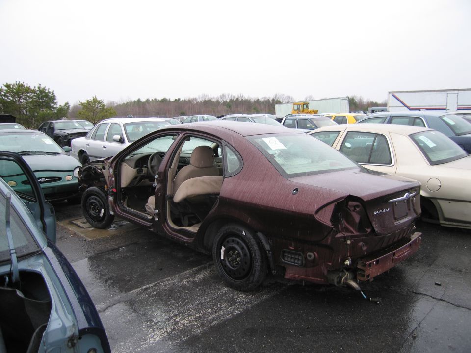 Maroon sedan, rear damaged, doors open, in a junkyard
