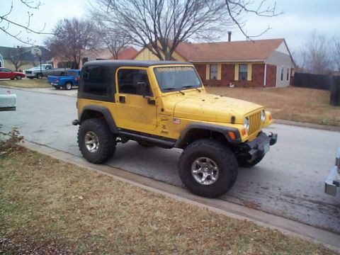 1978 Ford Bronco - A yellow Jeep Wrangler is parked on the side of the road in front of a house.