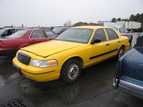 1991 Ford LTD Crown Victoria - A yellow sedan sits in an outdoor lot under an overcast sky, with other vehicles visible.