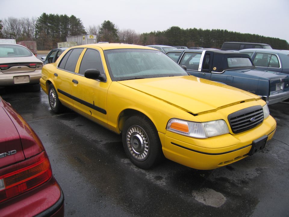 Yellow 1991 Ford Crown Victoria LTD taxi cab parked in lot with other cars