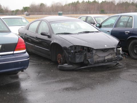 1991 Ford LTD Crown Victoria - A black sedan sits in a lot with its front end heavily damaged and one wheel missing.
