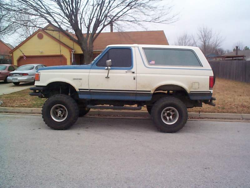 Lifted white and blue Ford Bronco parked on a street