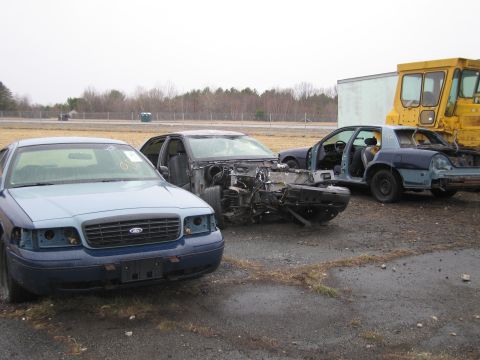 1991 Ford LTD Crown Victoria - Three Ford Crown Victorias are parked in a lot, all appear to be damaged or stripped for parts.