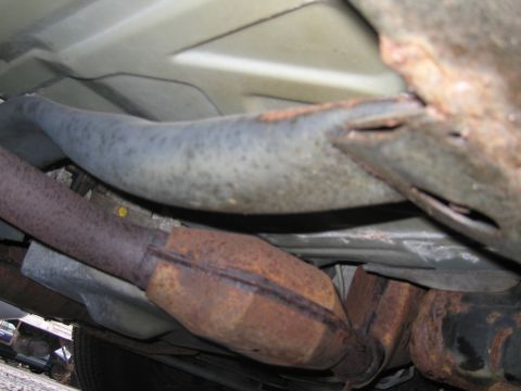 1991 Ford LTD Crown Victoria - The underside of the vehicle shows significant rust on the exhaust system components.