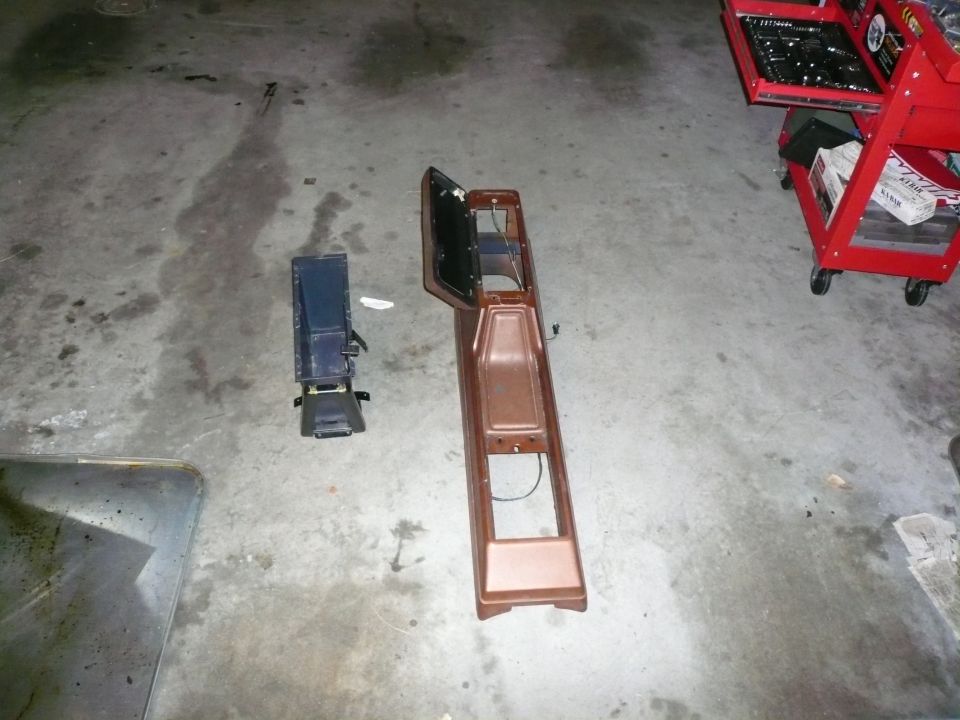 Brown and black car interior console parts on a concrete floor