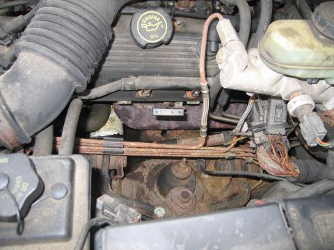 1991 Ford LTD Crown Victoria - The engine bay of a 1991 Ford Crown Victoria LTD displays significant rust on the exhaust manifold and surrounding components.