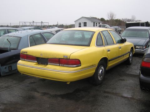 1991 Ford LTD Crown Victoria - Rear view of a yellow 1991 Ford Crown Victoria LTD in a junkyard setting.