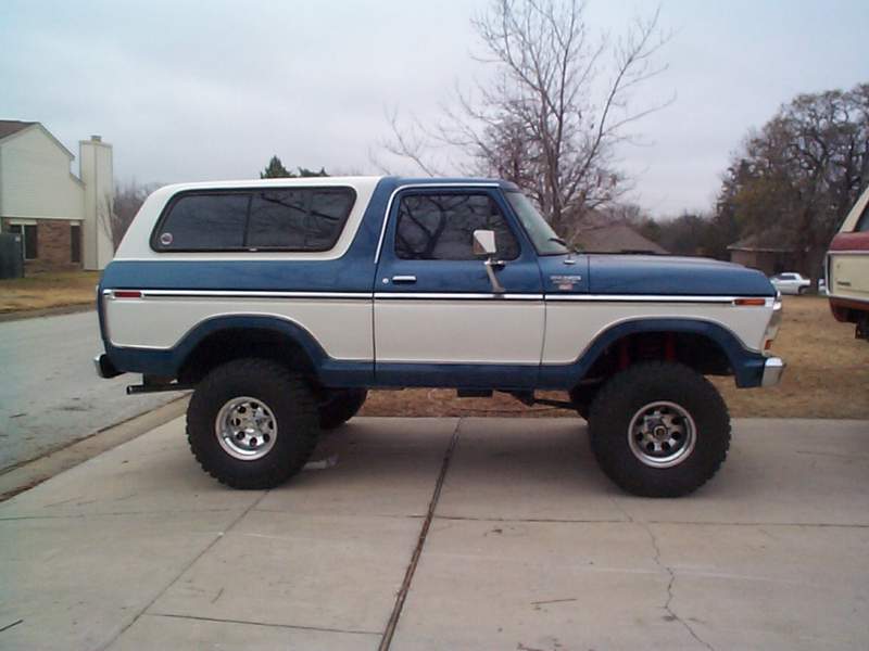 Blue and white 1978 Ford Bronco lifted with large tires, side view