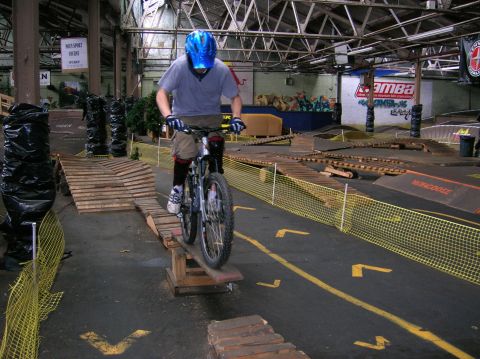 1997 Ford Probe - A rider on a bicycle carefully maneuvers through an indoor obstacle course wooden ramps and barriers.