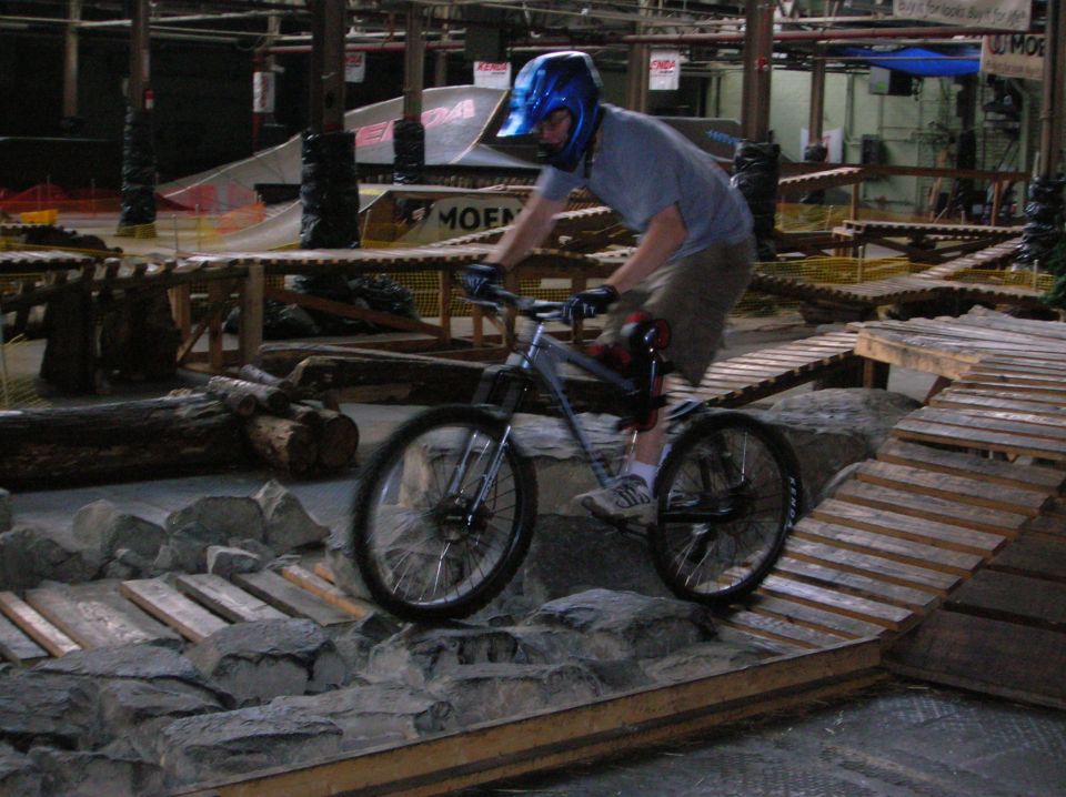Person in helmet riding a mountain bike over rocks and wooden ramps