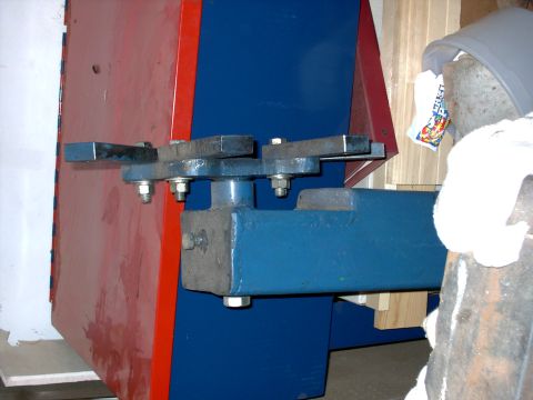 1965 Ford Mustang - Close-up view of a mechanical part with blue and red painted metal components and visible bolts.