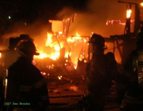 1989 Ford Bronco - Firefighters are silhouetted against a burning building at night, with flames engulfing the structure.